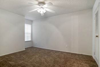 A room with a ceiling fan and carpeted floor